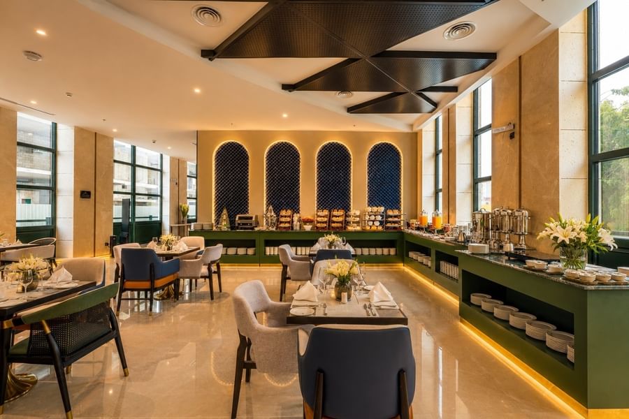 Roshen Restaurant interior with buffet counter and set dining tables under geometric ceiling at Naviti by Warwick Jeddah