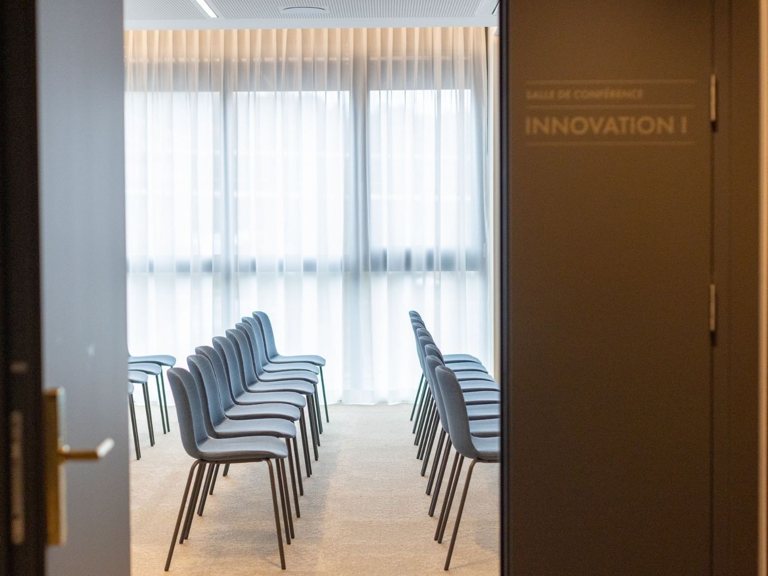 Open door view into conference room Innovation I at Hotel des Innovations with theater-style seating and sheer curtains