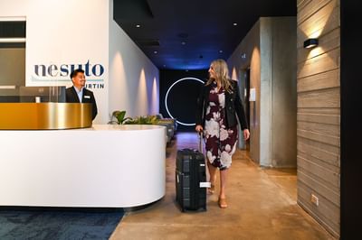 Guest walking by the reception at Nesuto Curtin Perth Hotel