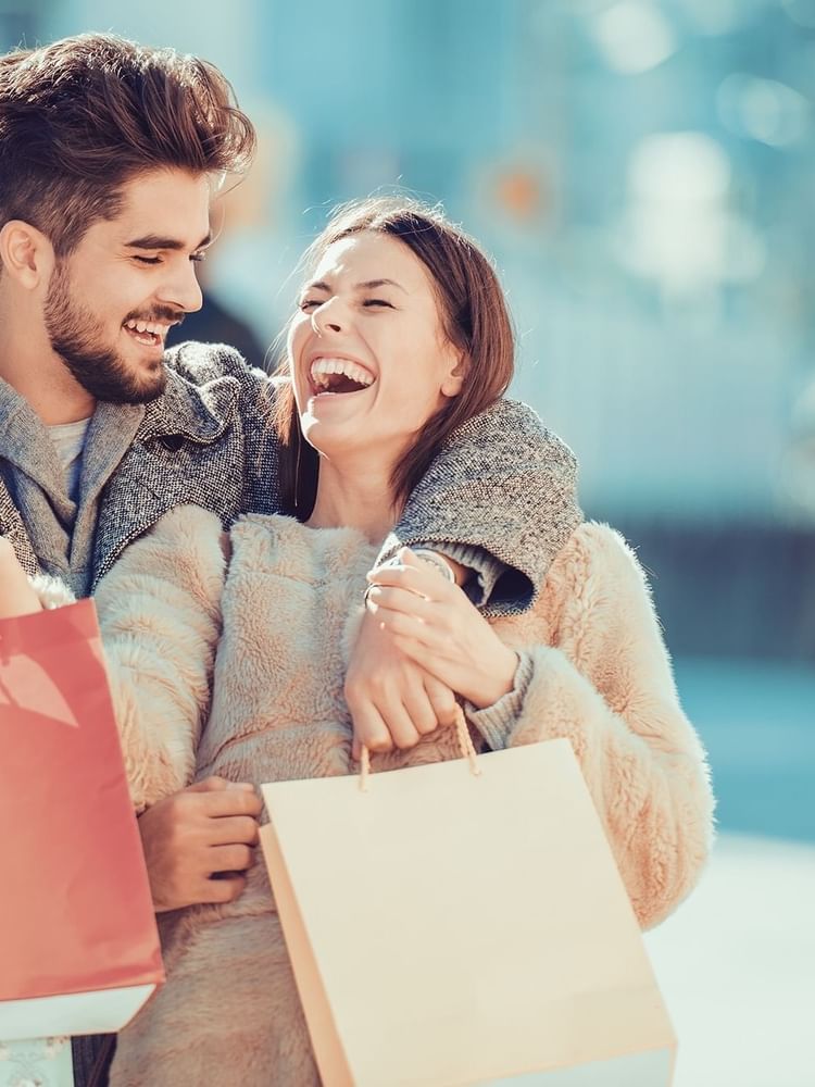 Couple laughing together while carrying shopping bags on a sunny day at Part Dieu mall near Warwick Reine Astrid - Lyon