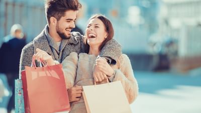Couple laughing together while carrying shopping bags on a sunny day at Part Dieu mall near Warwick Reine Astrid - Lyon