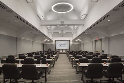 Modern conference room with rows of tables and black chairs facing a projection screen at Aramark Chauncey Conference Center