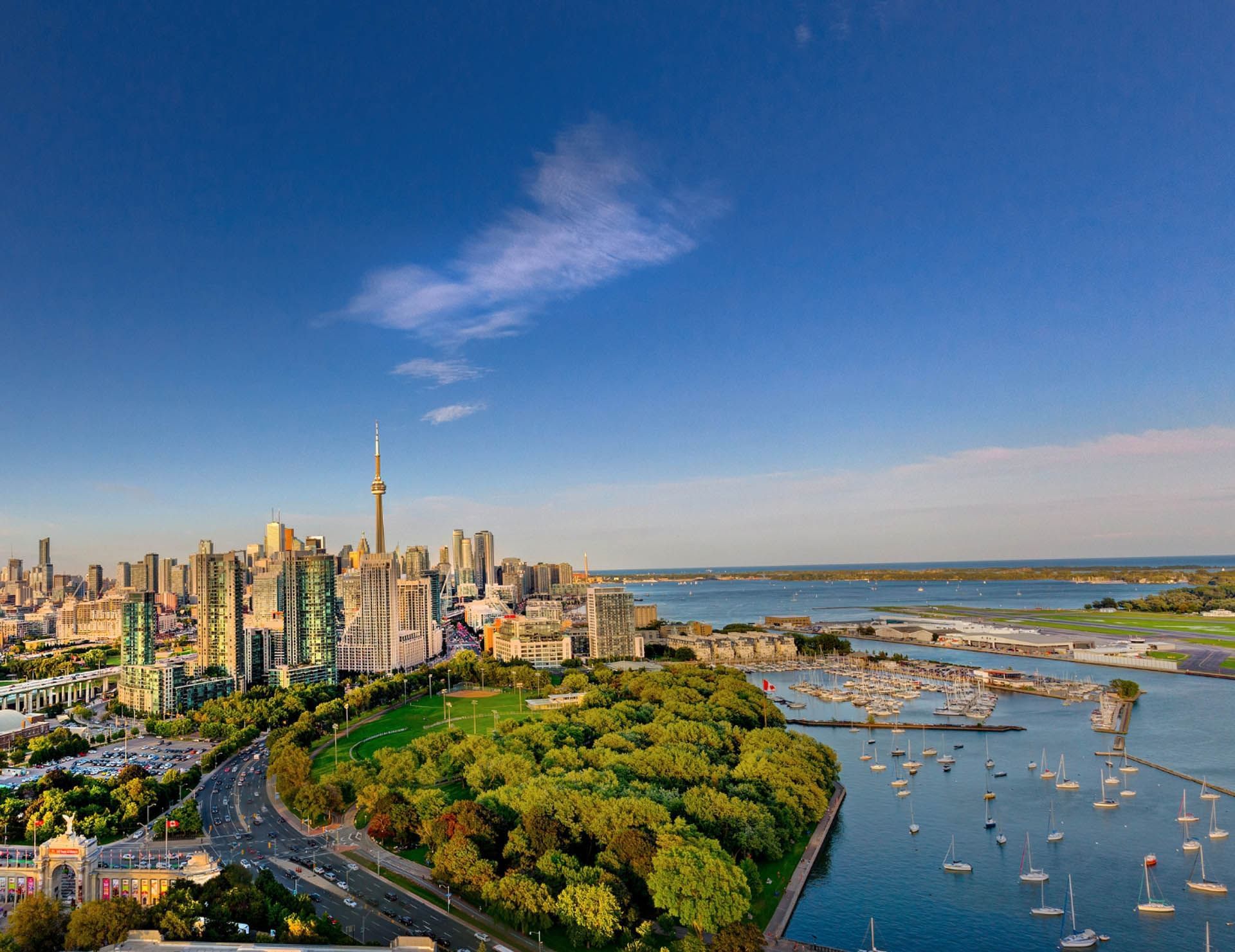 Aerial view of green parkland and marina beside Lake Ontario facing the iconic city skyline near Hotel X Toronto