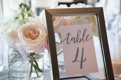 Table number in a frame by pink roses in a glass vase on a white tablecloth at The J House Greenwich