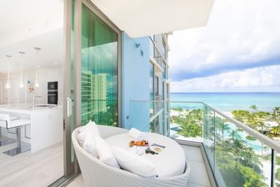 Balcony view with a plate of pastries and a magazine, overlooking palm trees and the sea in N703, The Residences at Seafire