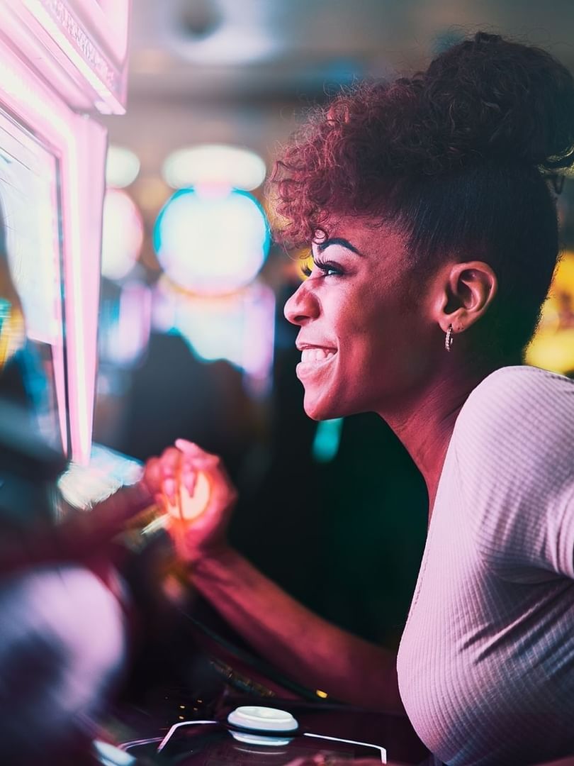 Lady playing arcade games by neon lights under a bun hairstyle at Atlantis Casino near Warwick Paradise Island Bahamas