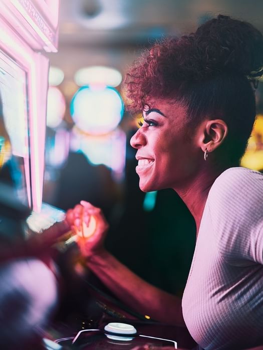 Lady playing arcade games by neon lights under a bun hairstyle at Atlantis Casino near Warwick Paradise Island Bahamas