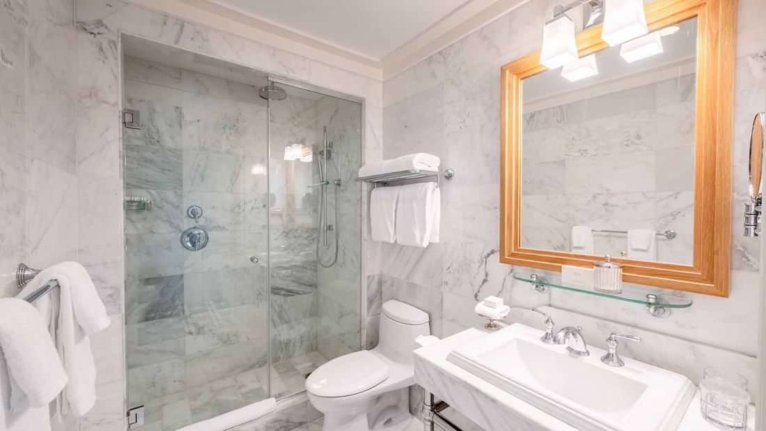 Courtyard Deluxe Fireplace King bathroom with mirror, vanity, and glass-enclosed shower at El Prado Hotel