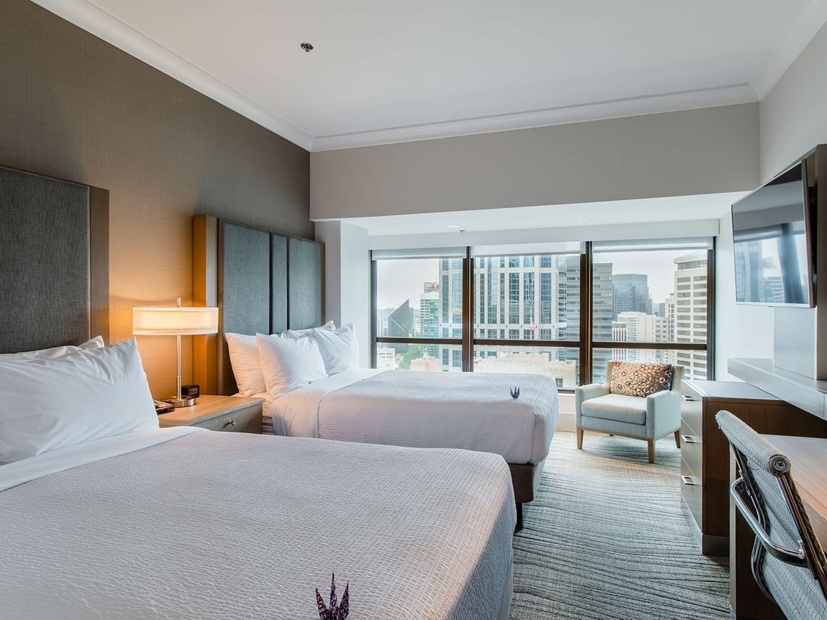 Hotel guestroom with two beds, TV, and desk