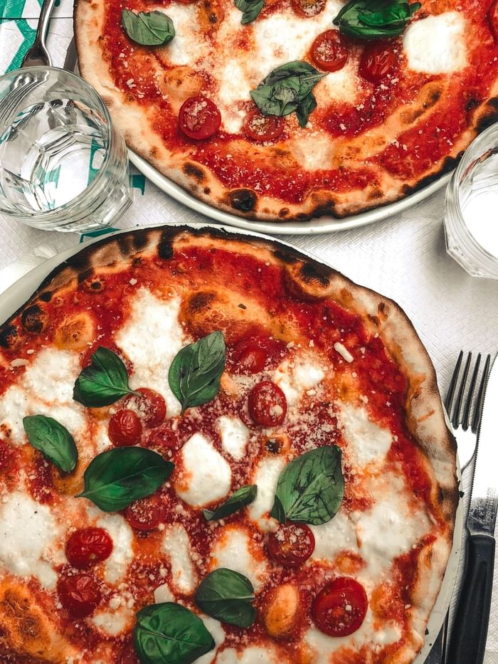 Close-up of a pizza with water glasses served in a restaurant near Anaheim Portofino Inn & Suites