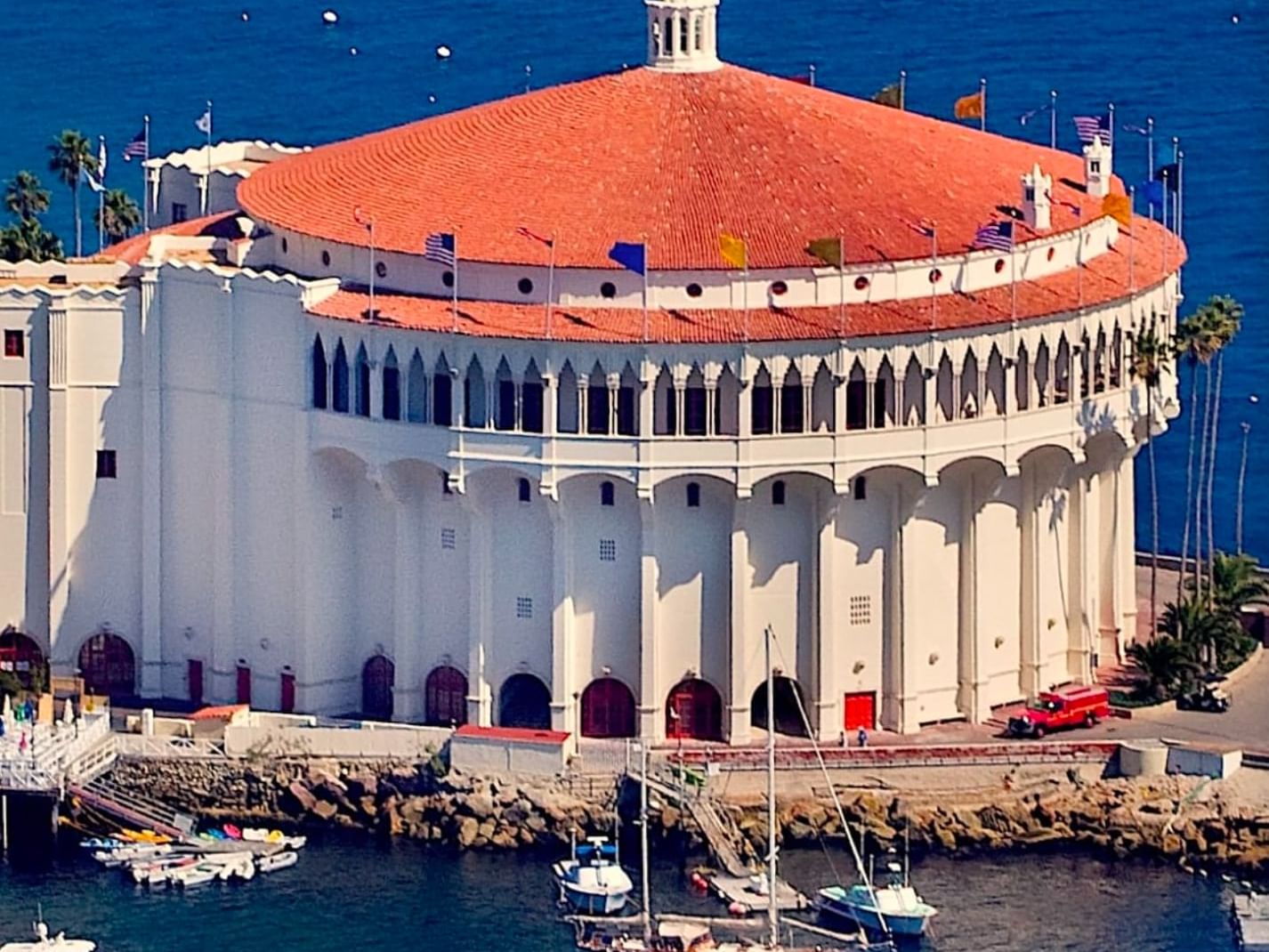 Aerial view of a building with a red-tiled dome roof beside a marina with boats at Catalina Island Company