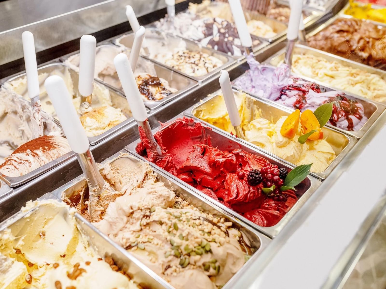 Variety of colorful gelato flavors displayed in metal containers in II Gelatone near The Glam Hotel