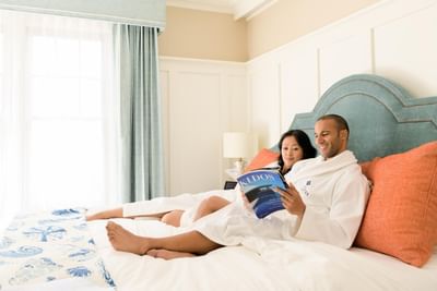 Couple reading a book on the bed wearing robes at Catalina Island Company