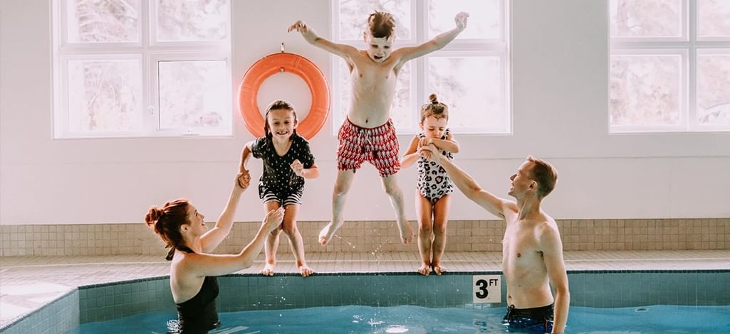 Three children jump into a hotel pool in Canmore with their parents' assistance.