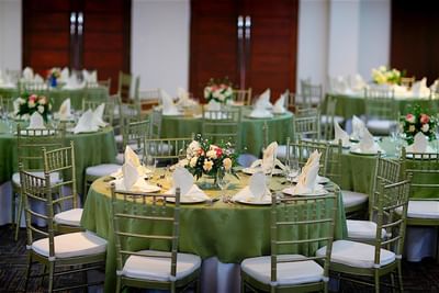 A formal dining area at Hotel Mykonos with circular tables adorned with green linens and floral centerpieces