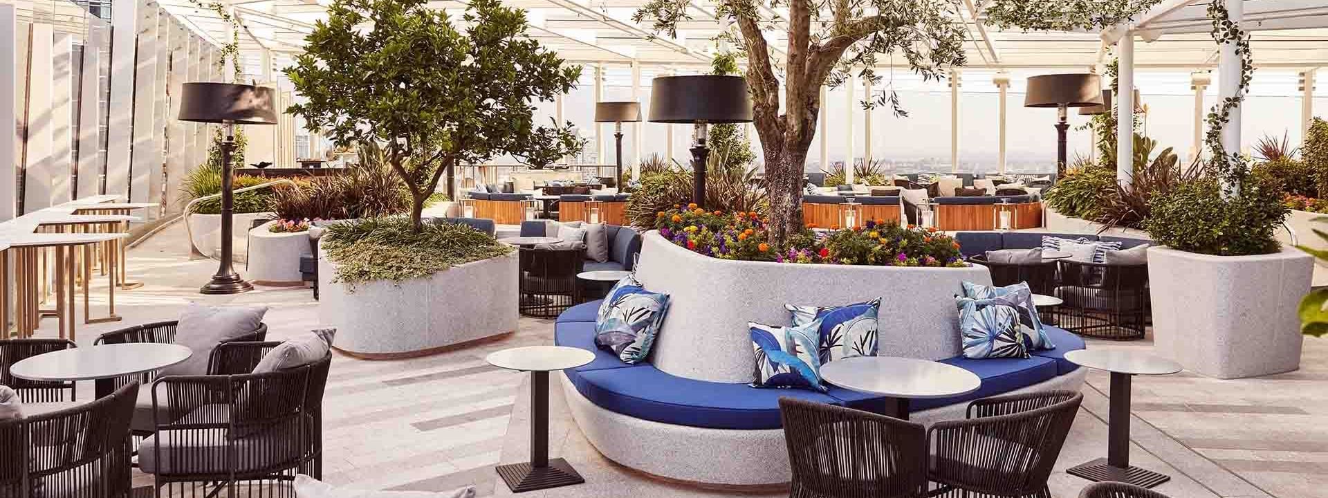 Elegant outdoor terrace with modern furniture, plants, and trellis roofing in CIRQ at Crown Hotels