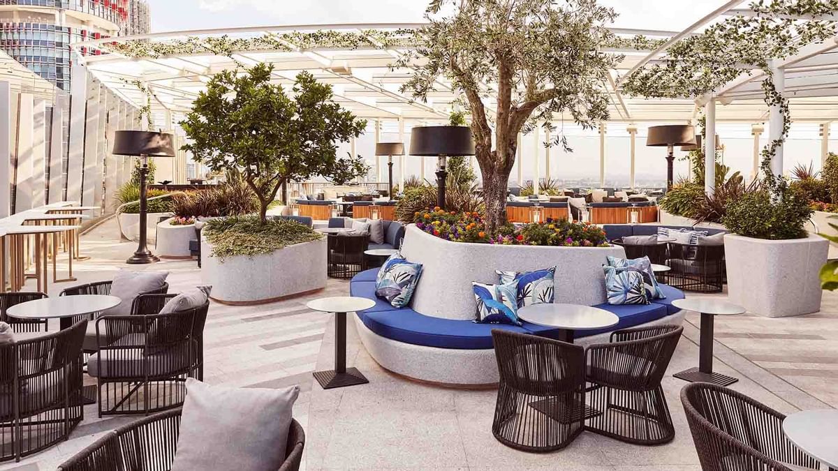 Elegant outdoor terrace with modern furniture, plants, and trellis roofing in CIRQ at Crown Hotels