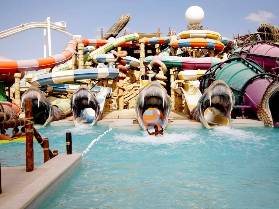 Colorful water slides with inflatable rings splashing into a pool at Yas Waterworld in Abu Dhabi near DAMAC Hotels & Resorts