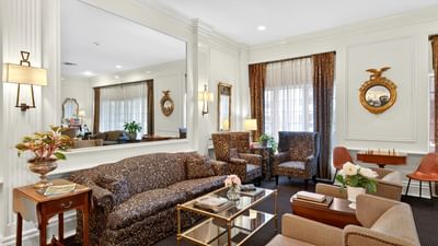 Patterned sofa near a glass coffee table & armchairs beside a large framed mirror in the sitting area at Avon Old Farms Hotel