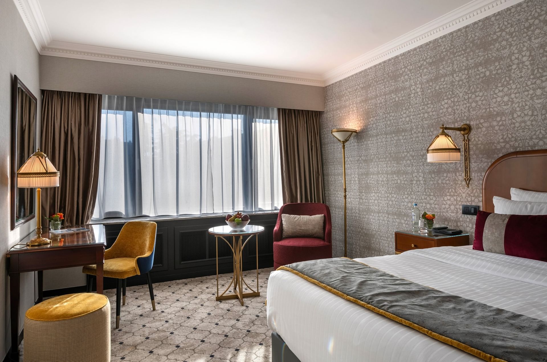 Bed beside velvet armchair and a wooden desk with yellow chair in Superior Room at Hotel Barsey by Warwick