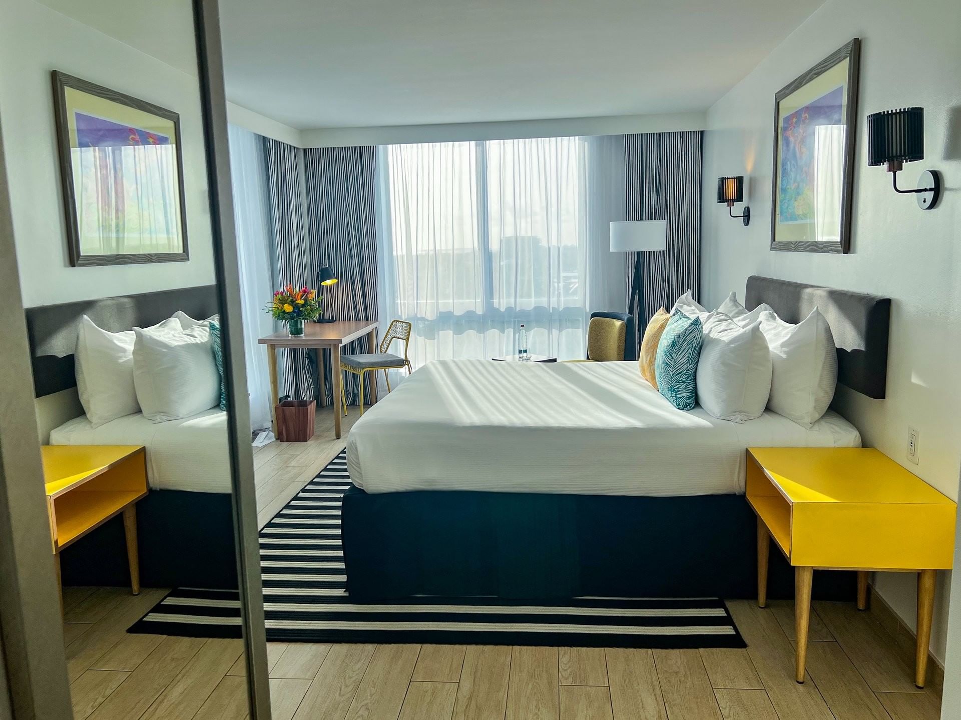 King bed between yellow nightstands by a desk under large windows in Water view at Warwick Paradise Island Bahamas