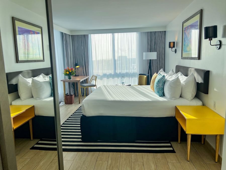 King bed between yellow nightstands by a desk under large windows in Water view at Warwick Paradise Island  Bahamas