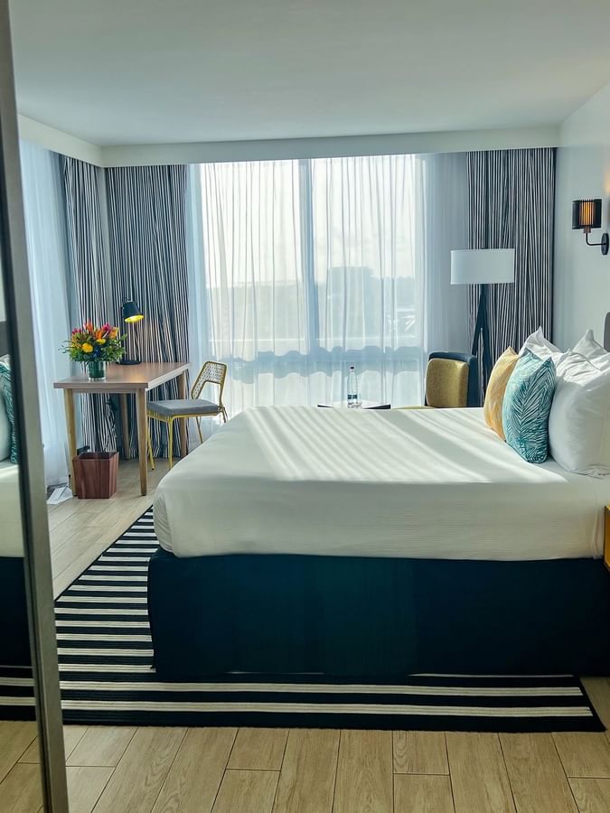 King bed between yellow nightstands by a desk under large windows in Water view at Warwick Paradise Island  Bahamas