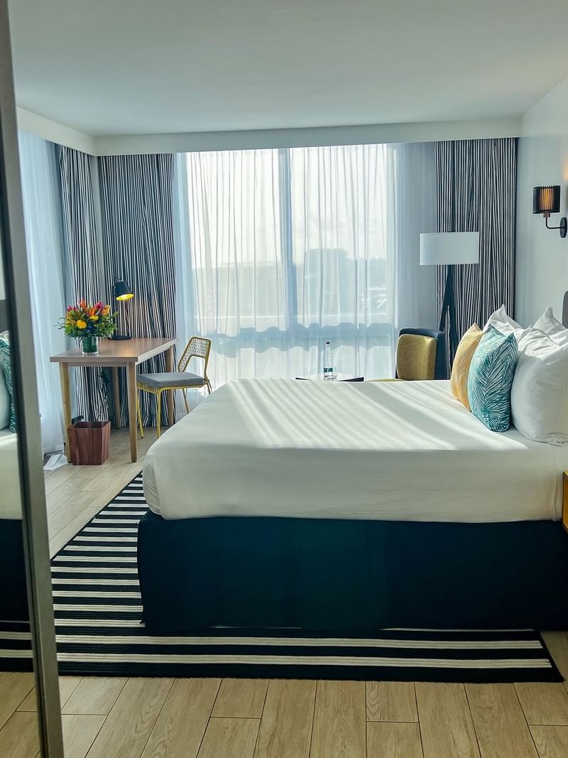King bed between yellow nightstands by a desk under large windows in Water view at Warwick Paradise Island  Bahamas