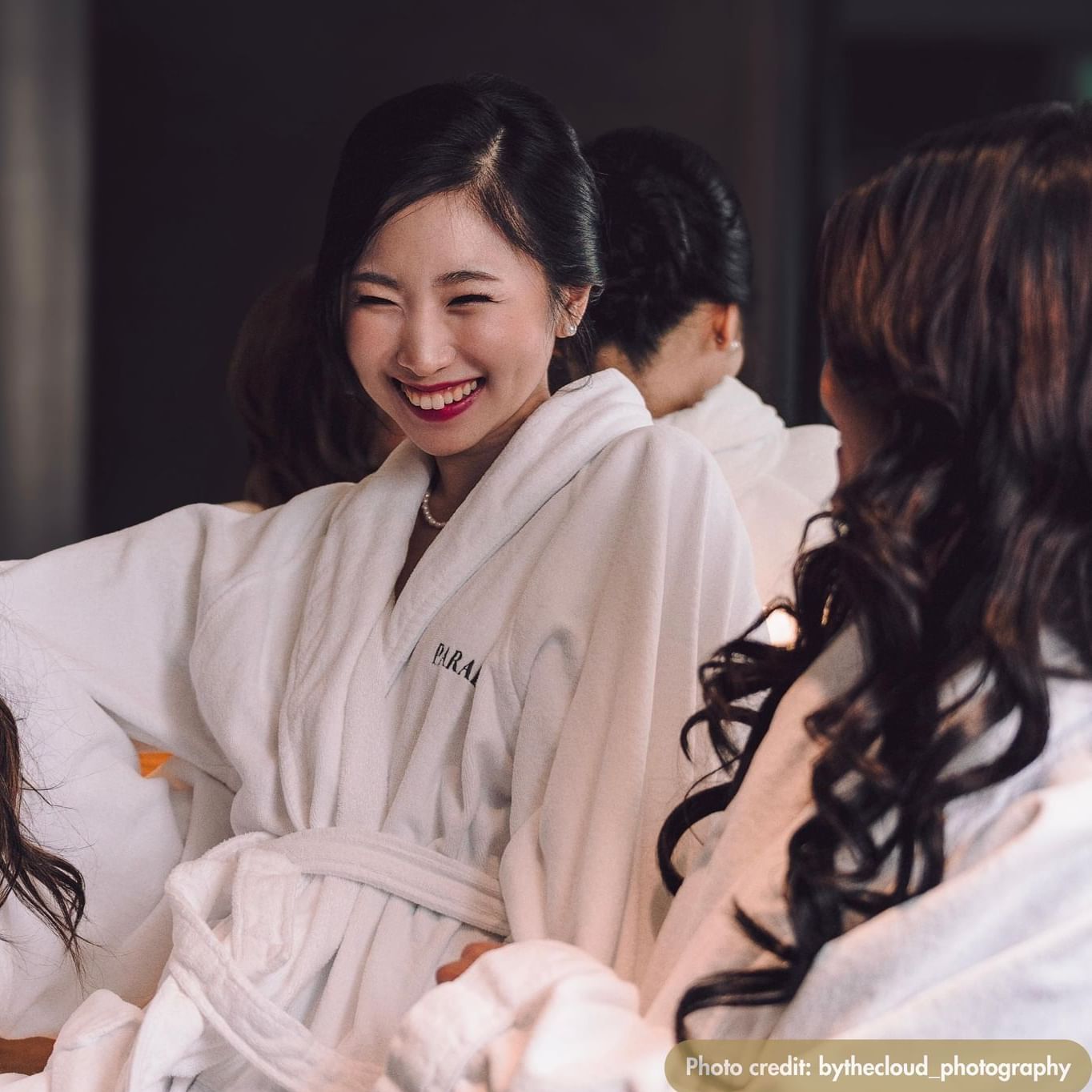 Three women in bathrobes smile and laugh together while enjoying No-Taxi-Night at Paradox Vancouver.