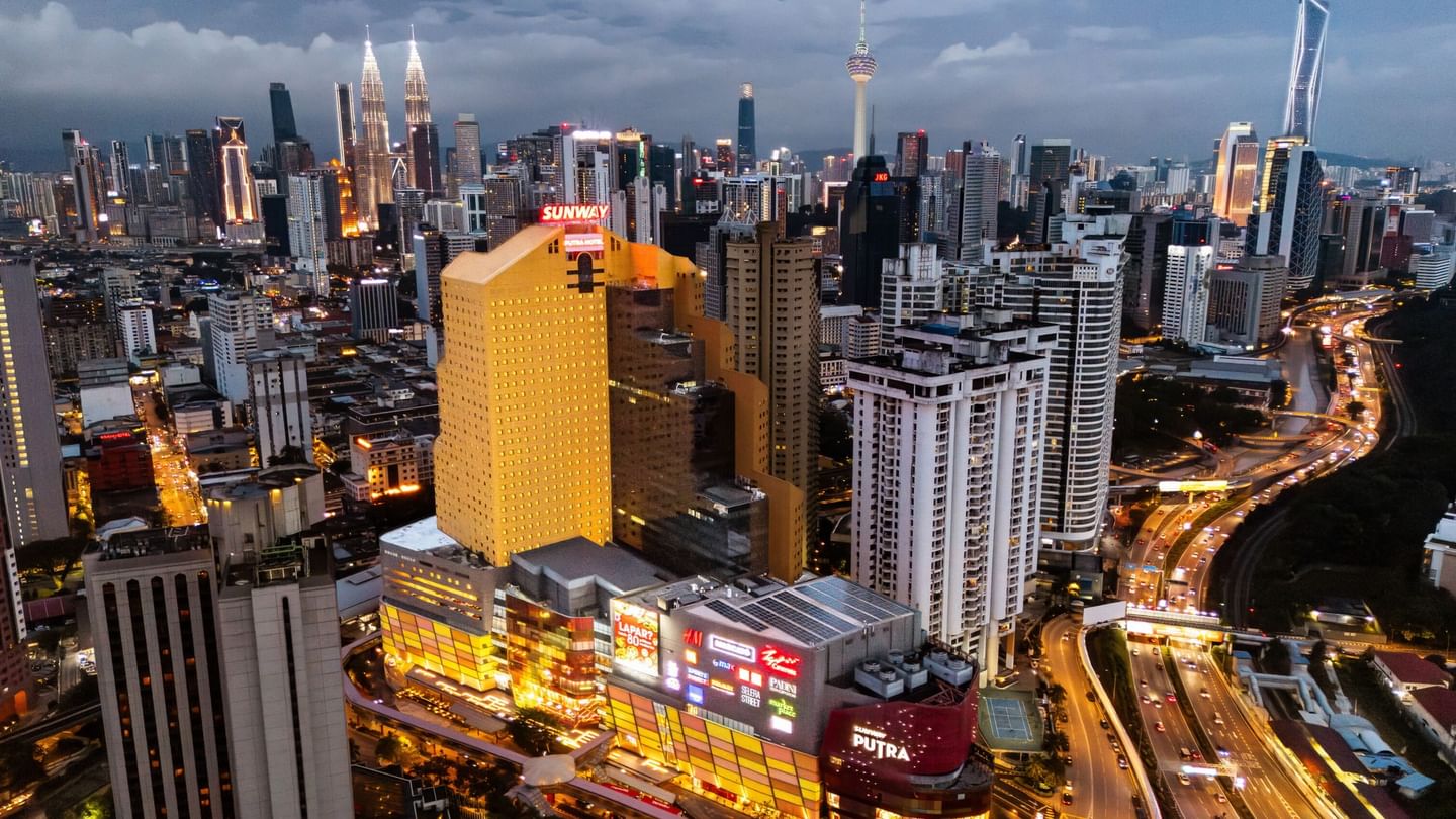 Vibrant cityscape at dusk featuring glowing skyscrapers and busy roads near Sunway Putra Hotel
