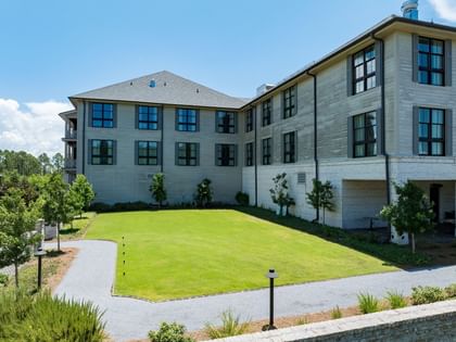Magnolia Lawn with lush green grass and paved walkways beside a modern building at Camp Creek Inn in Inlet Beach.