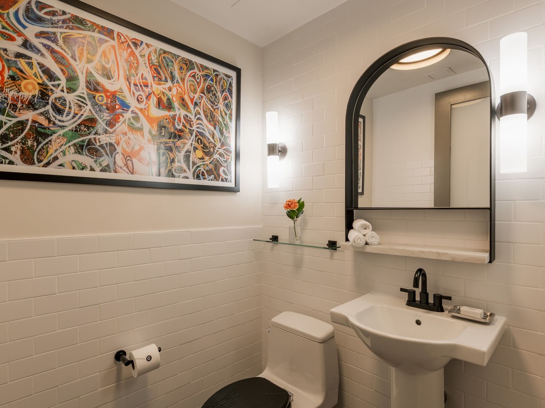 White Manhattan Suite bathroom with toilet, sink, and abstract art at Gansevoort Meatpacking NYC in New York.
