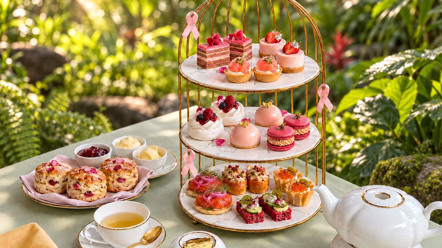 Elegant three-tier stand with pink pastries, scones, and tea service displayed on an outdoor table surrounded by lush greenery at The Banjaran Hotsprings Retreat celebrating Pink October