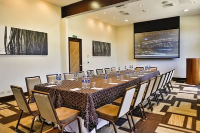 Modern conference room with a long table, chair and projector screen at El Mangroove Hotel