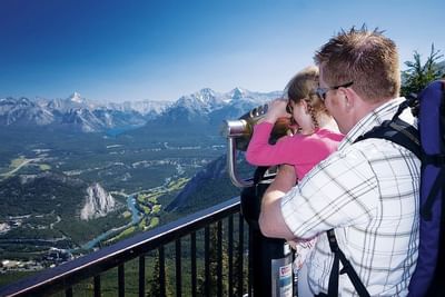 Child using binoculars to view the mountains from Sulphur Mountain near Blackstone Mountain Lodge