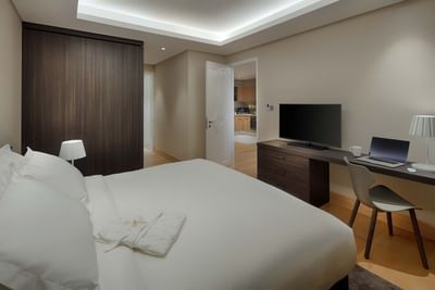 spacious guestroom with king bed, tv and work area