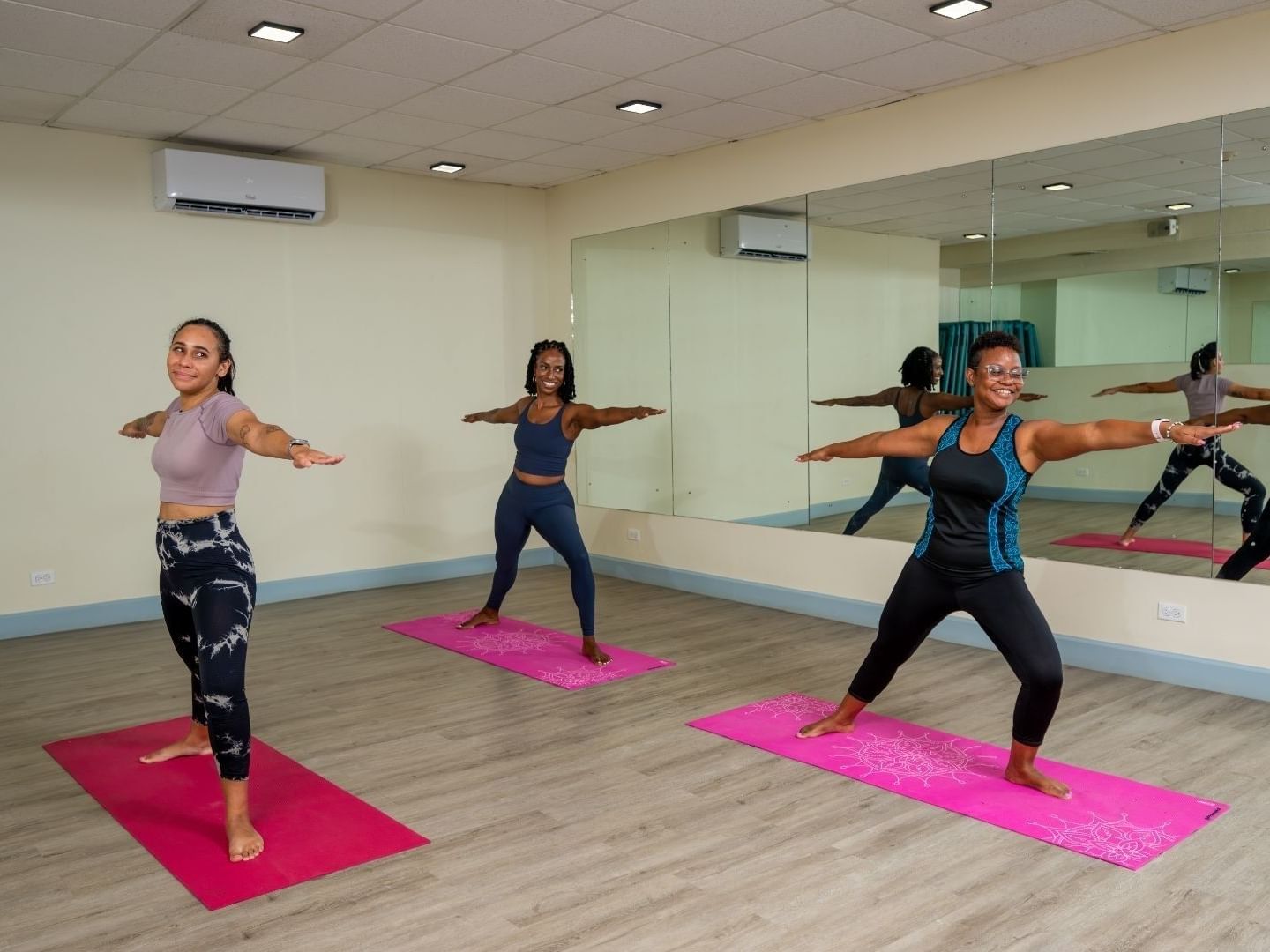 Group doing yoga poses on pink mats in a mirrored studio at Savannah Beach Hotel.