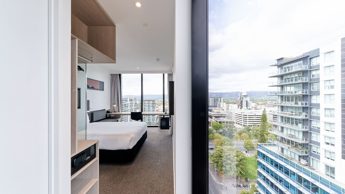 Deluxe Corner Room One Queen Bed with a large window offering panoramic city views, and a comfortable bed at Ibis Adelaide