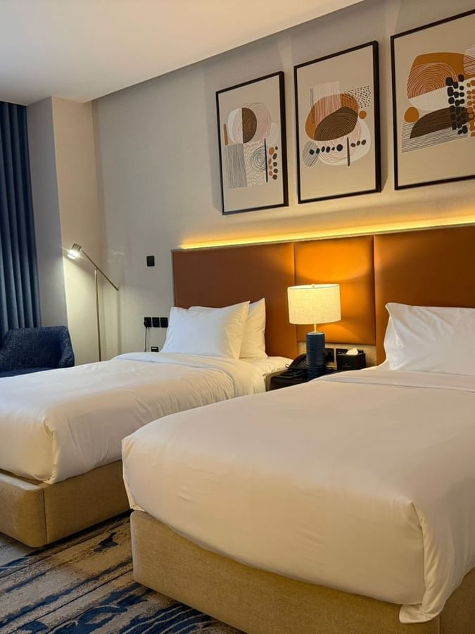 Two beds under wall art and couches near the window in Club Room at Warwick Jeddah Hotel & Spa