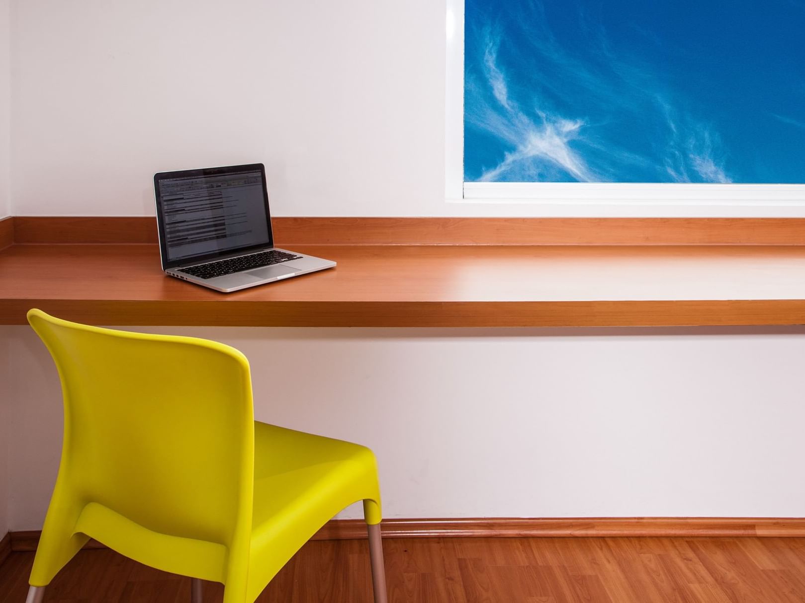 Ordenador portátil sobre un escritorio de pared con silla, One Hotels
