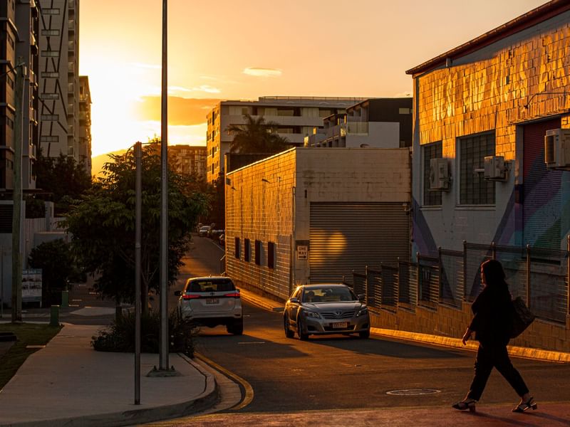 Sunset on a city street with a pedestrian crossing the road in West End near Sofitel Brisbane Central