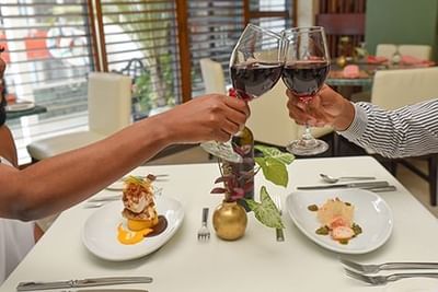 A couple toasting their wine glasses in a restaurant at Courtleigh Hotel & Suites