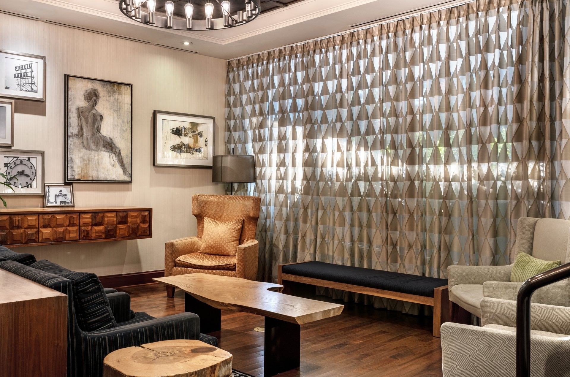 Lobby area featuring tan armchairs by a wooden table under a ring chandelier near Warwick Seattle