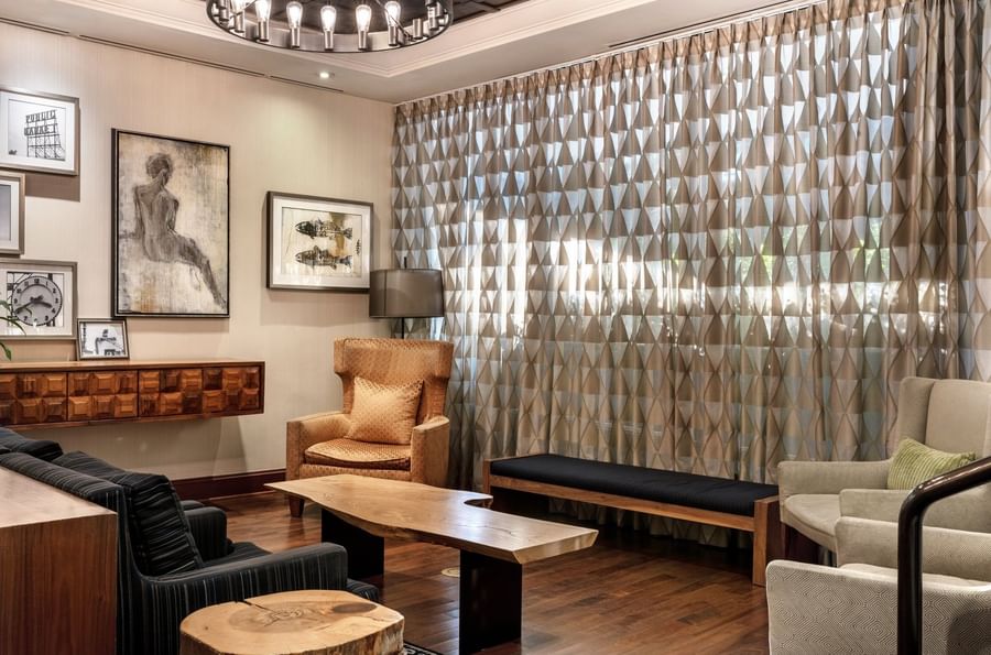 Lobby area featuring tan armchairs by a wooden table under a ring chandelier near Warwick Seattle