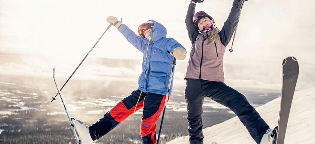 Two people pose at the top of a ski hill near Canmore, excited to start their run.