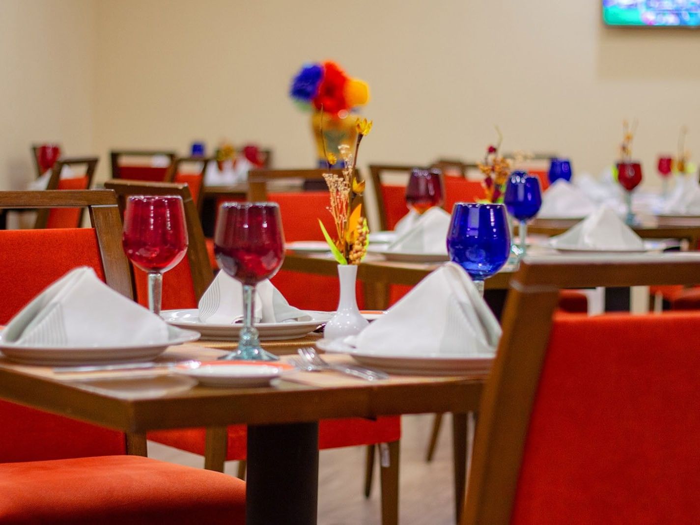 Close up of a Cualli table set with white napkins and red and blue glass at Camino Real Aeropuerto Mexico
