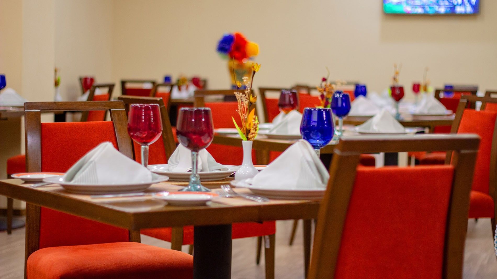 Close up of a Cualli table set with white napkins and red and blue glass at Camino Real Aeropuerto Mexico