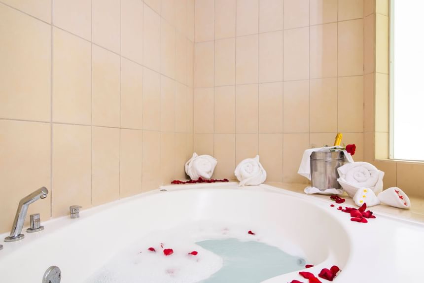 A bathtub decorated with rose petals in a room at Fiesta Resort