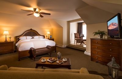 Lodge Suite featuring a king-sized bed, a TV with a chair and a window at The Stanley Hotel