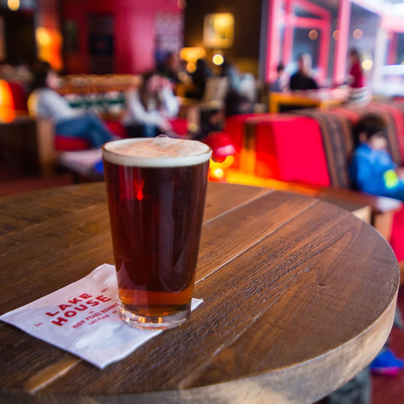 Beer glass and napkin on table with Lake House logo at Lake House Opening Ceremony Watch Party.